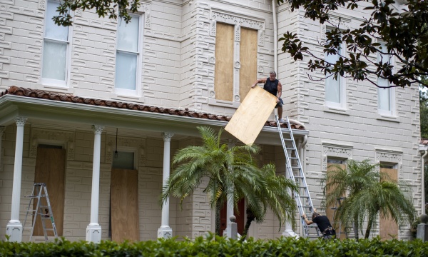 Two people work on boarding up a house in South Tampa Bay, Florida, on Tuesday, before Hurricane Ian hits the area.