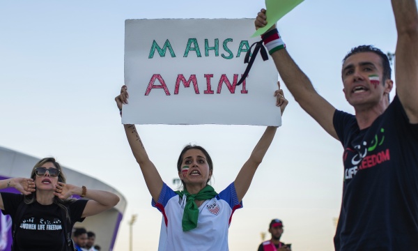 A woman at a protest in Qatar holds up a sign bearing the name of Mahsa Amini, the 22-year-old Iranian woman whose death in police custody sparked a nationwide protest movement.